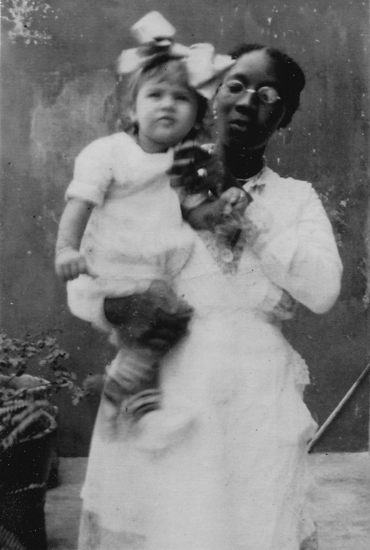 Een oude zwart-wit foto van Ena Maduro in de armen van haar yaya Matilda Martina.