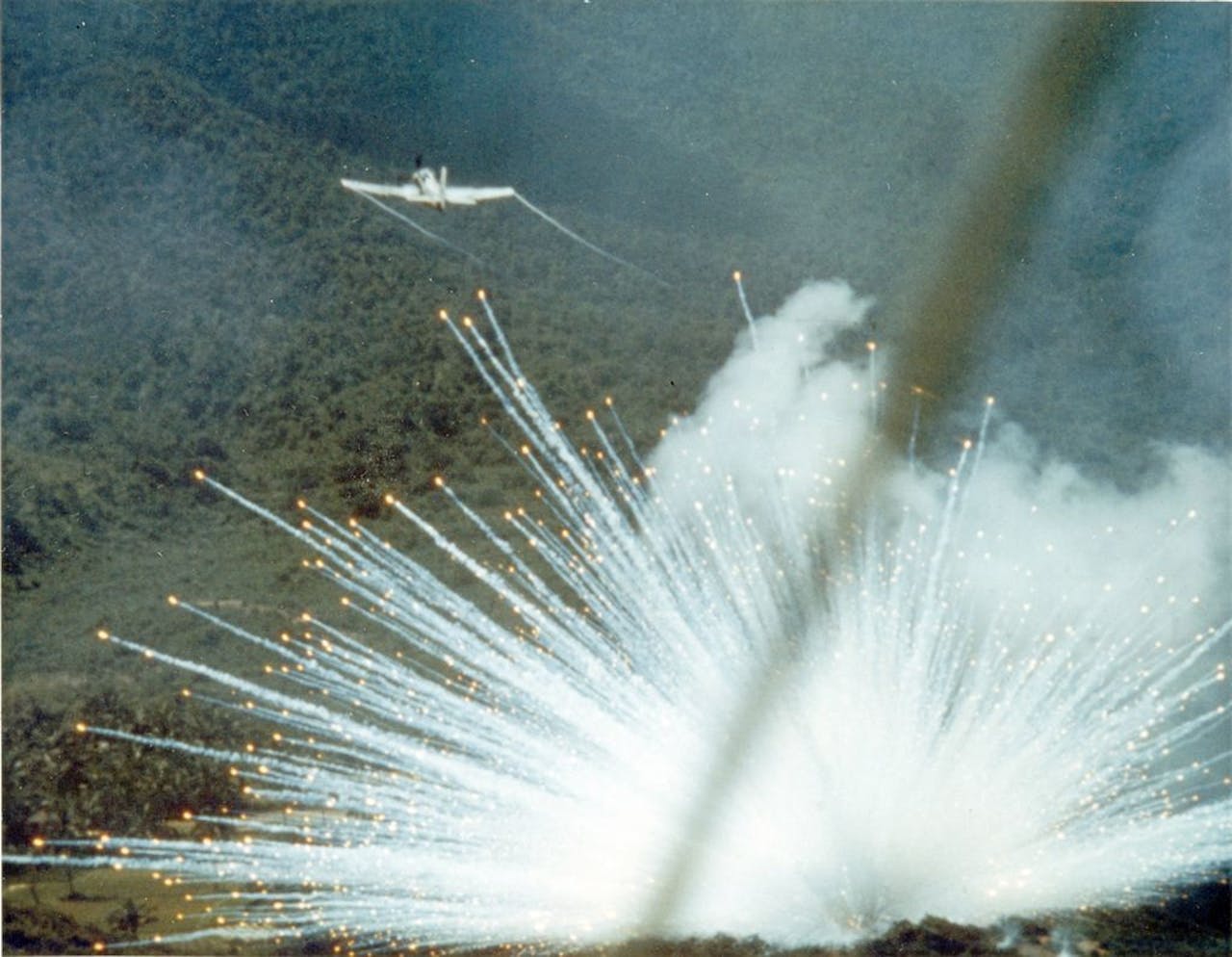 Een vliegtuig vliegt over een ontploffende witte fosforbom in Vietnam.