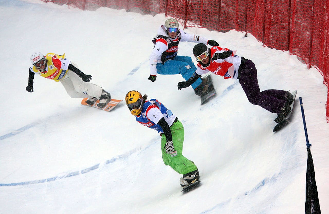 Bij boardercross nemen snowboarders het tegen elkaar op, zoals bij deze wedstrijd in Bad Gastein (Oostenrijk). Een groep mensen snowboardt een helling af.