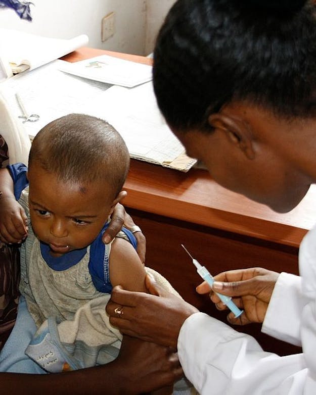 Niet alleen trekken de VS zich terug uit de WHO, ze zetten ook allerlei hulpprogramma’s stop, bijvoorbeeld rondom de bestrijding van hiv en polio. Buitenlands jongetje op de schoot van zijn moeder krijgt een prik van een arts