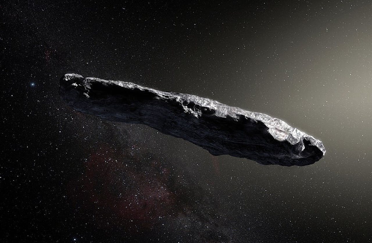 Een artistieke weergave van de astroïde Oumuamua getoond als een grote langwerpige metalige steen in de ruimte.