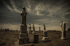 Grafstenen op een begraafplaats onder een sterrenhemel.