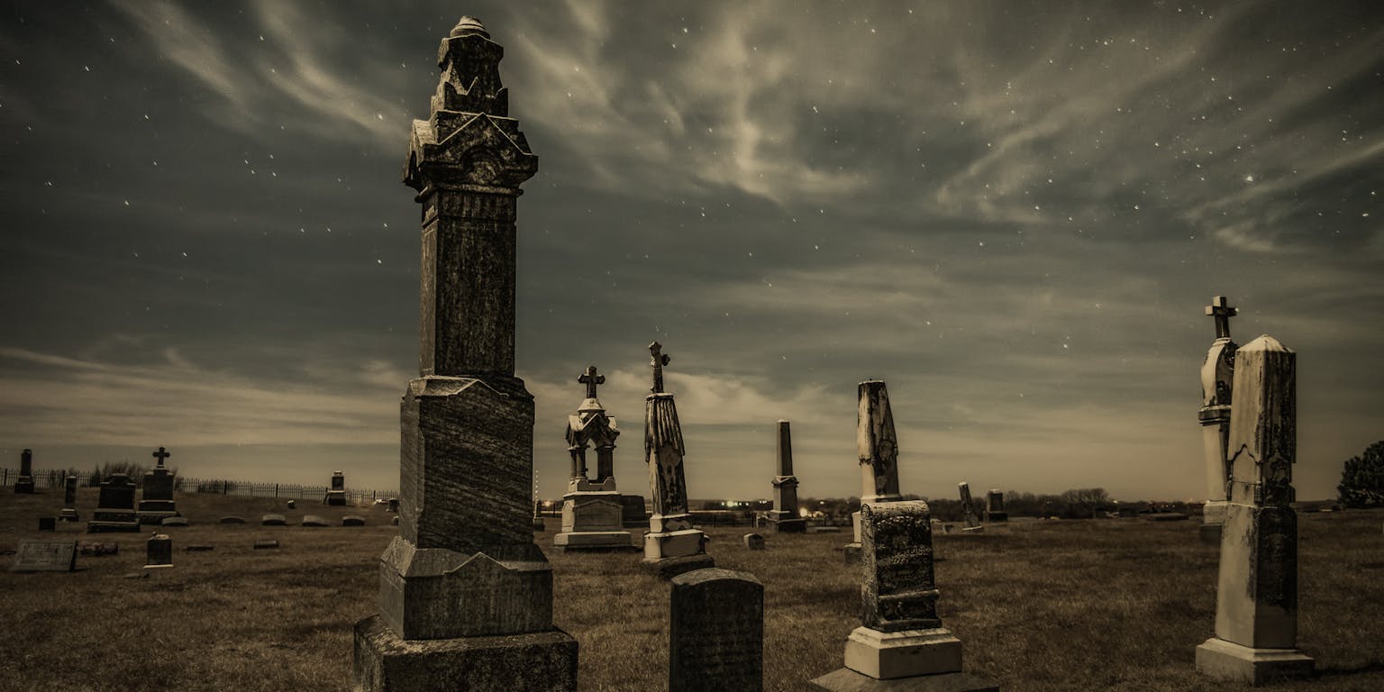 Grafstenen op een begraafplaats onder een sterrenhemel.