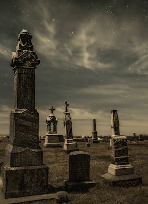 Grafstenen op een begraafplaats onder een sterrenhemel.