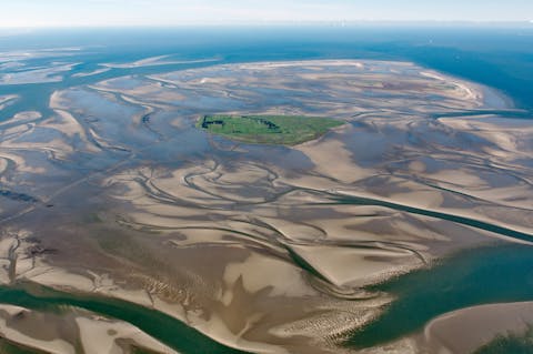 Het Duitse waddeneiland Neuwerk. De bodem van de Waddenzee bevat een complex patroon van geulen en ondiepere stukken, die continu veranderen.
