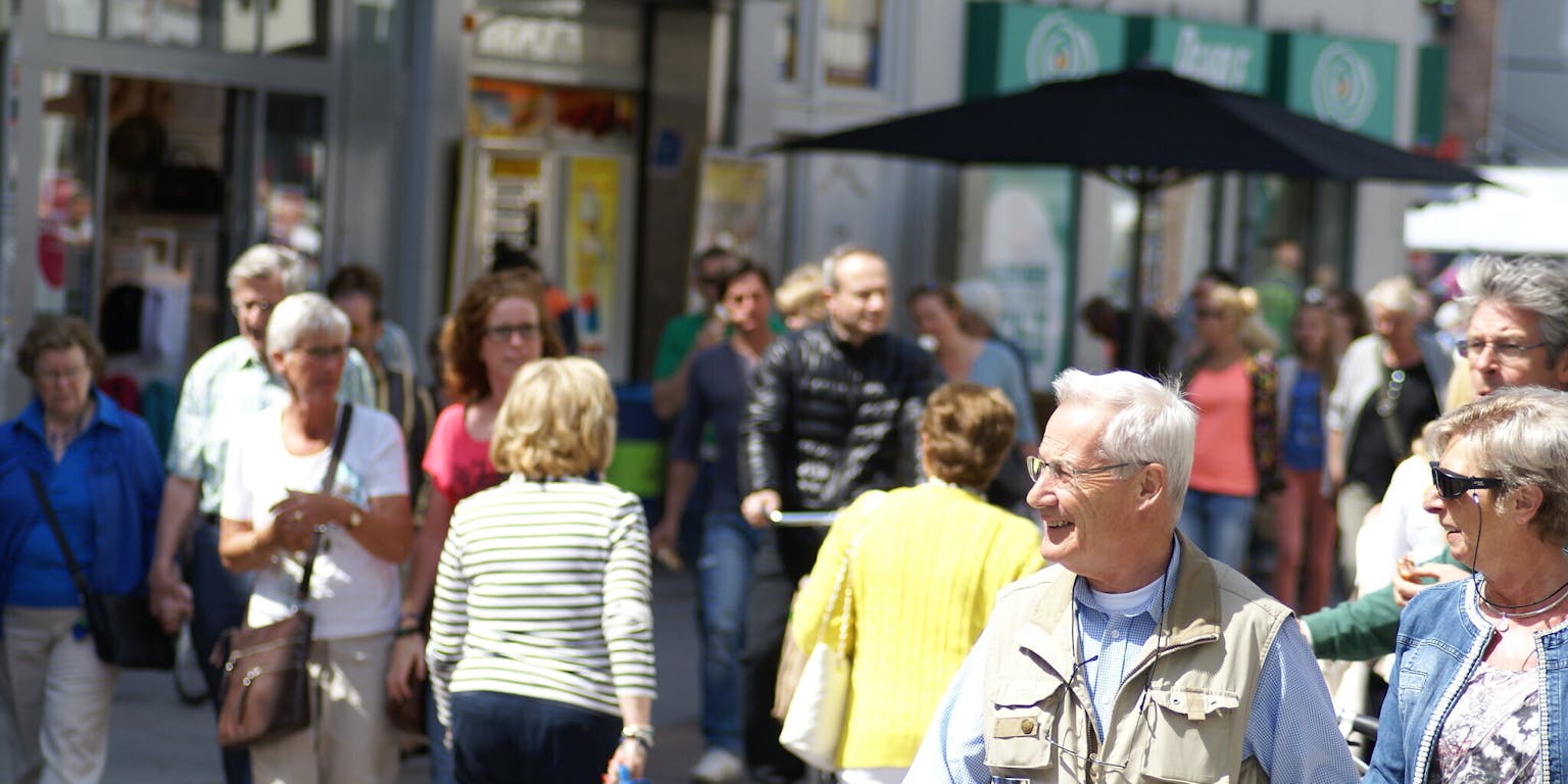 Winkelend publiek in een zonnige straat.