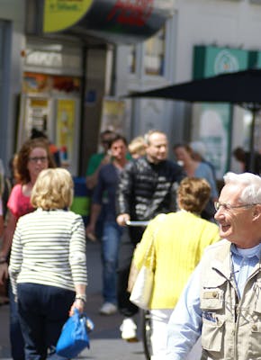 Winkelend publiek in een zonnige straat.