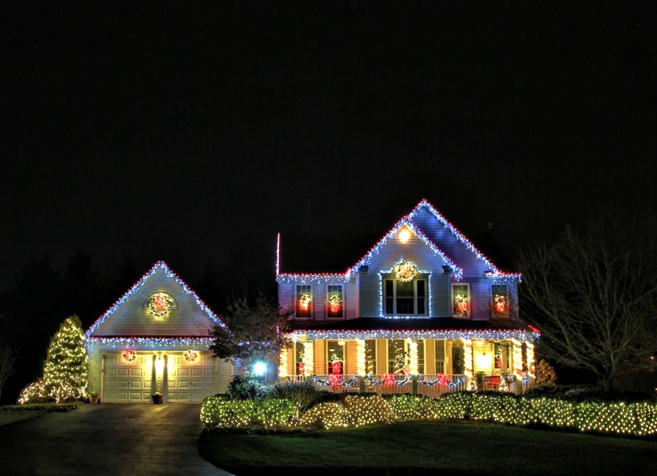 Een huis is versierd met kerstverlichting. Het is donker buiten.