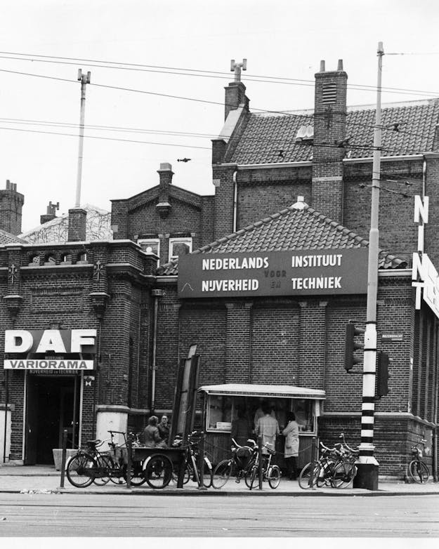 De voorloper van het huidige NEMO: het Nederlands Instituut voor Nijverheid en Techniek (NINT) in de jaren zeventig. Zwart/wit-foto van de ingang van het Nederlands Instituut voor Nijverheid en Techniek in Amsterdam, in de jaren zeventig