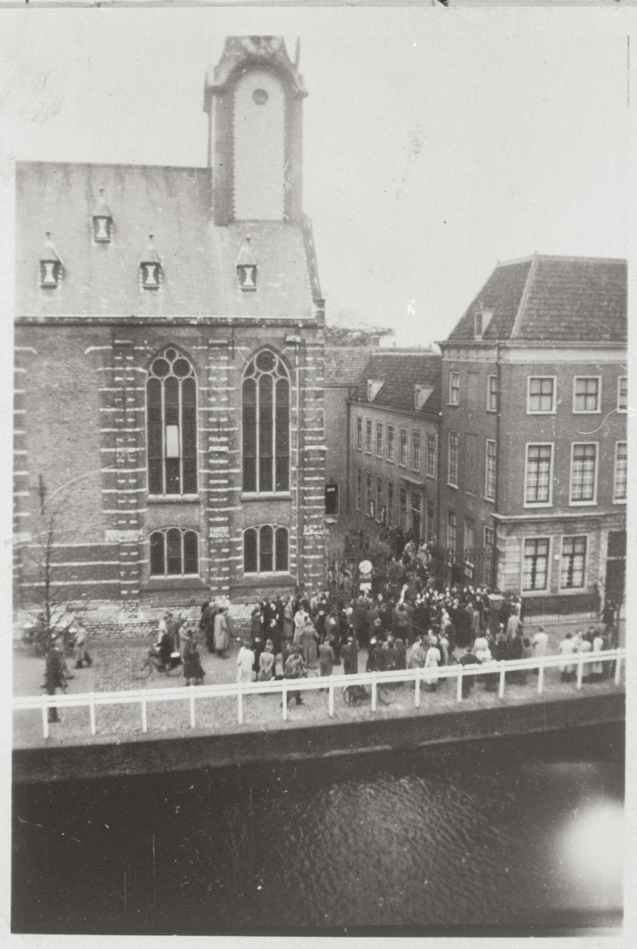 Een oude zwart-witfoto van mensen buiten een kerk.