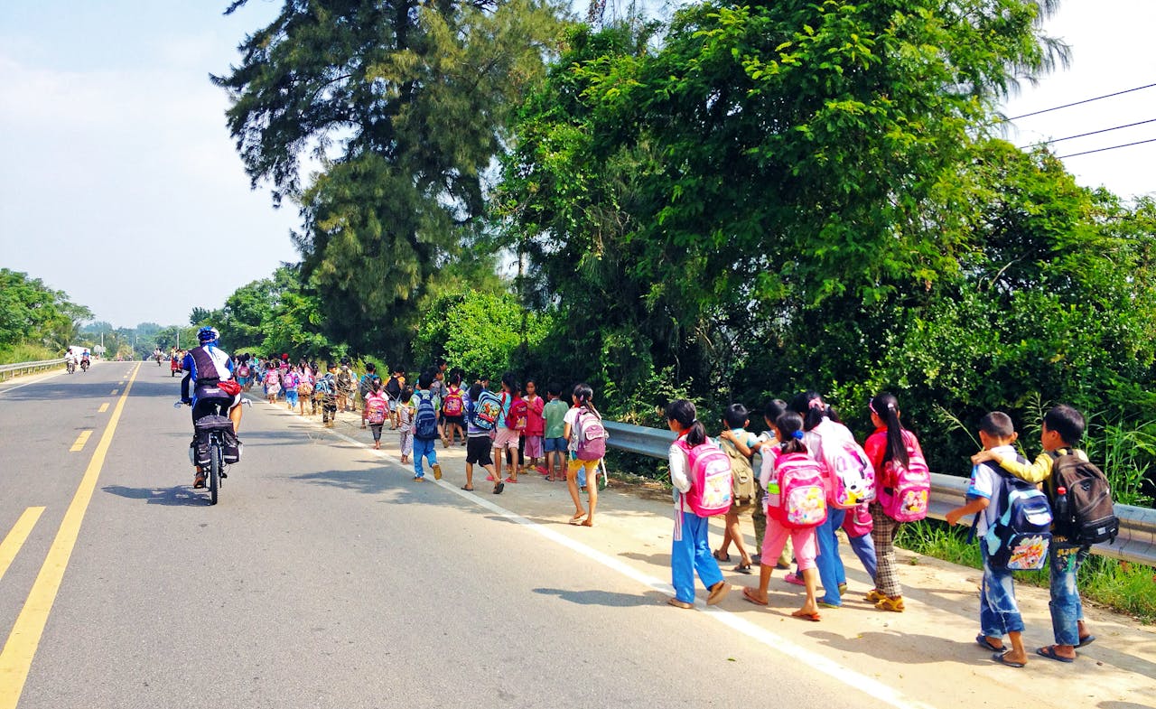Een groep basisschoolkinderen loopt in Azië over een weg.