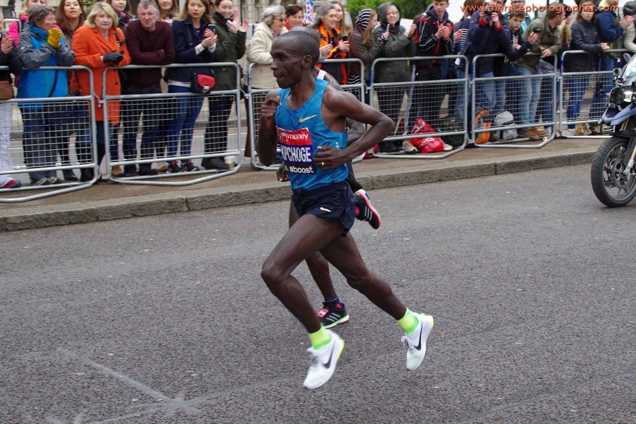 Hardloper Eliud Kipchoge rentop asfalt en het publiek kijkt toe