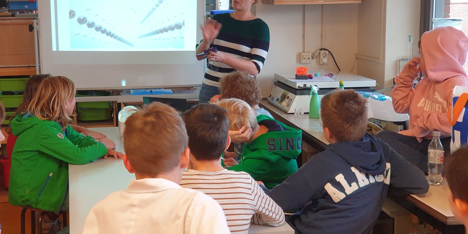 Een groep kinderen zit rond een tafel in een klaslokaal.