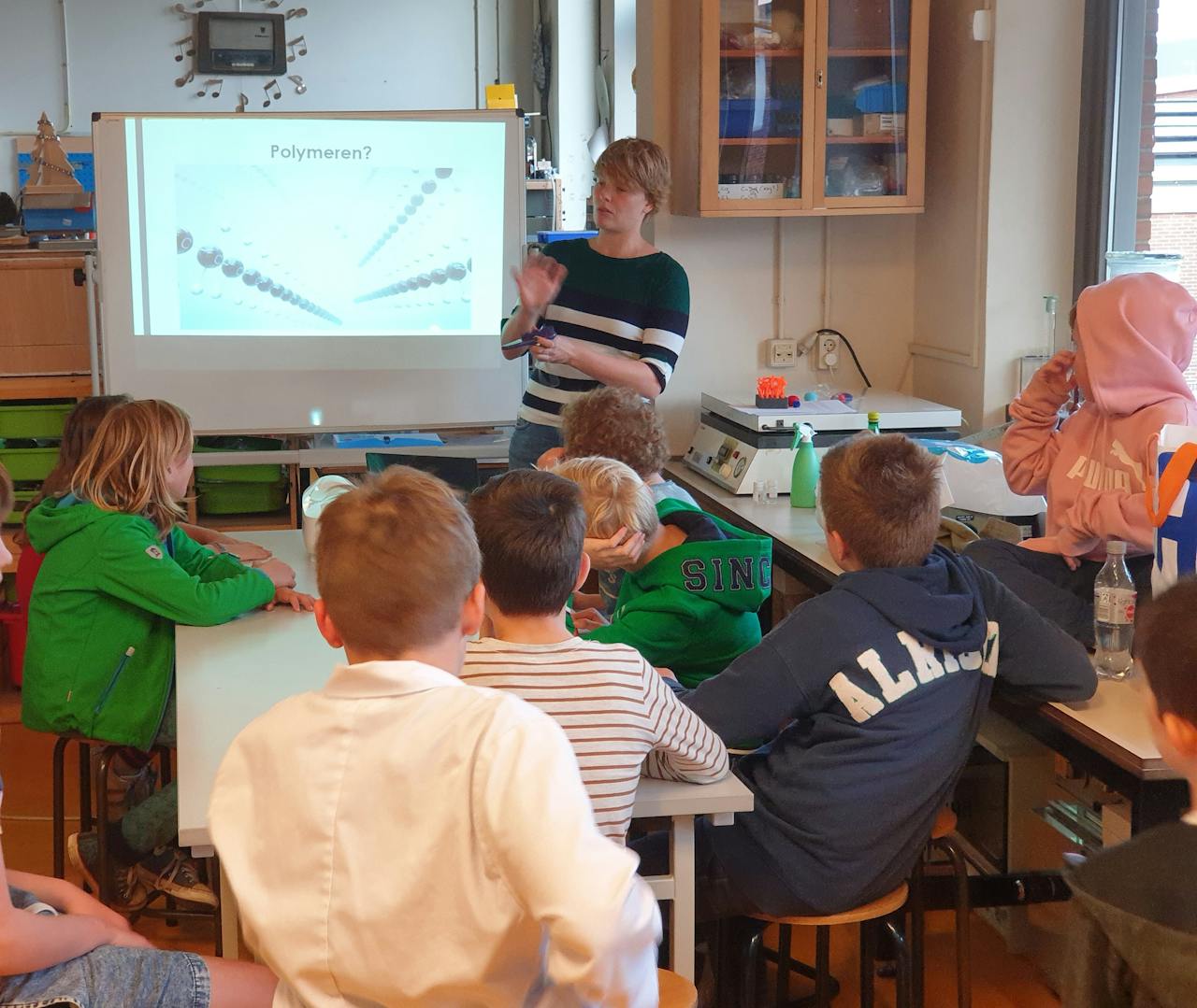 Een groep kinderen zit rond een tafel in een klaslokaal.