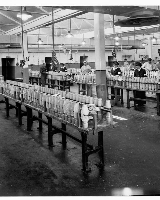Mannen en vrouwen die in een munitiefabriek werken, zwart-witfoto Mannen en vrouwen die in een munitiefabriek werken, zwart-witfoto