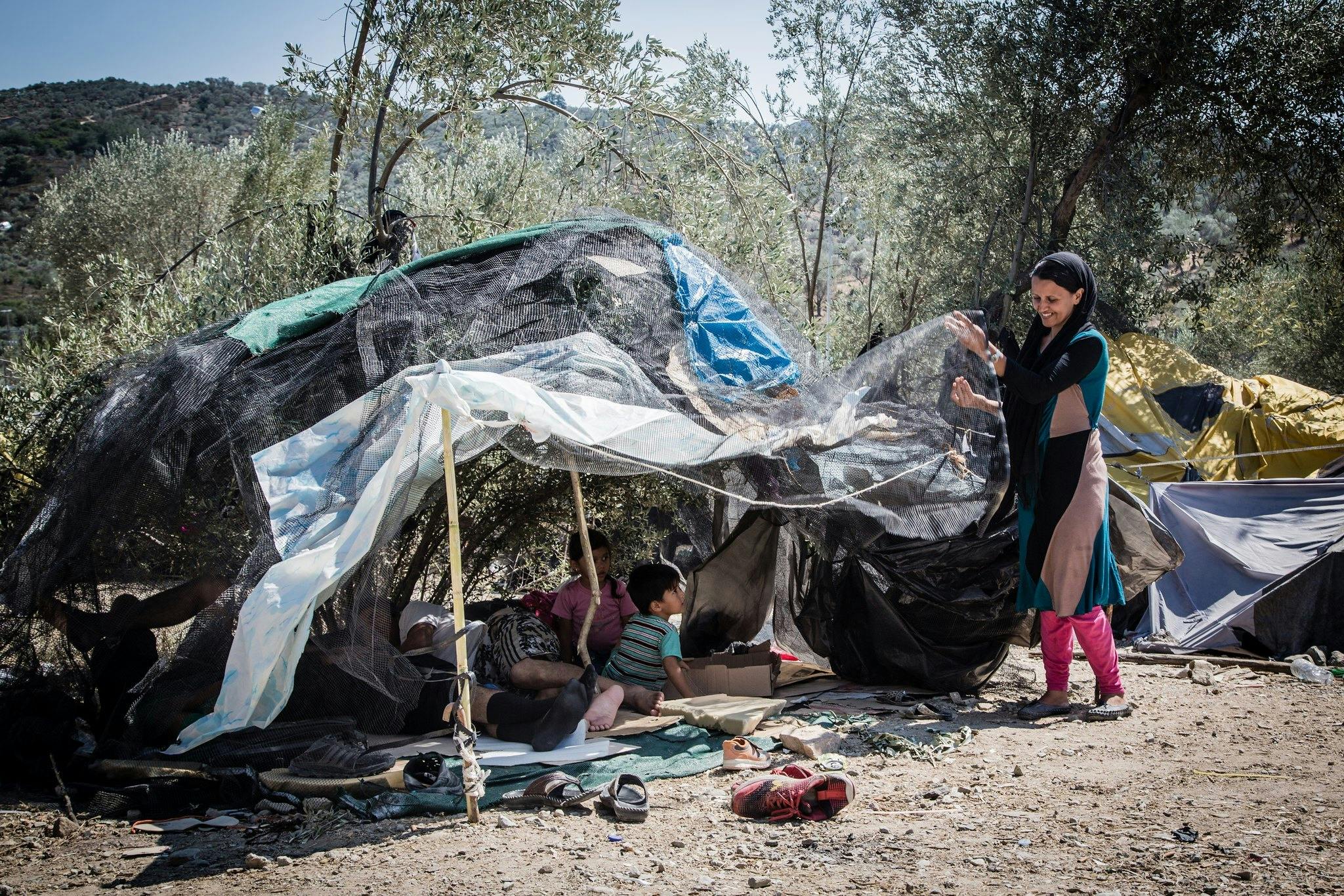 Een groep mensen staat naast een tent in het bos.