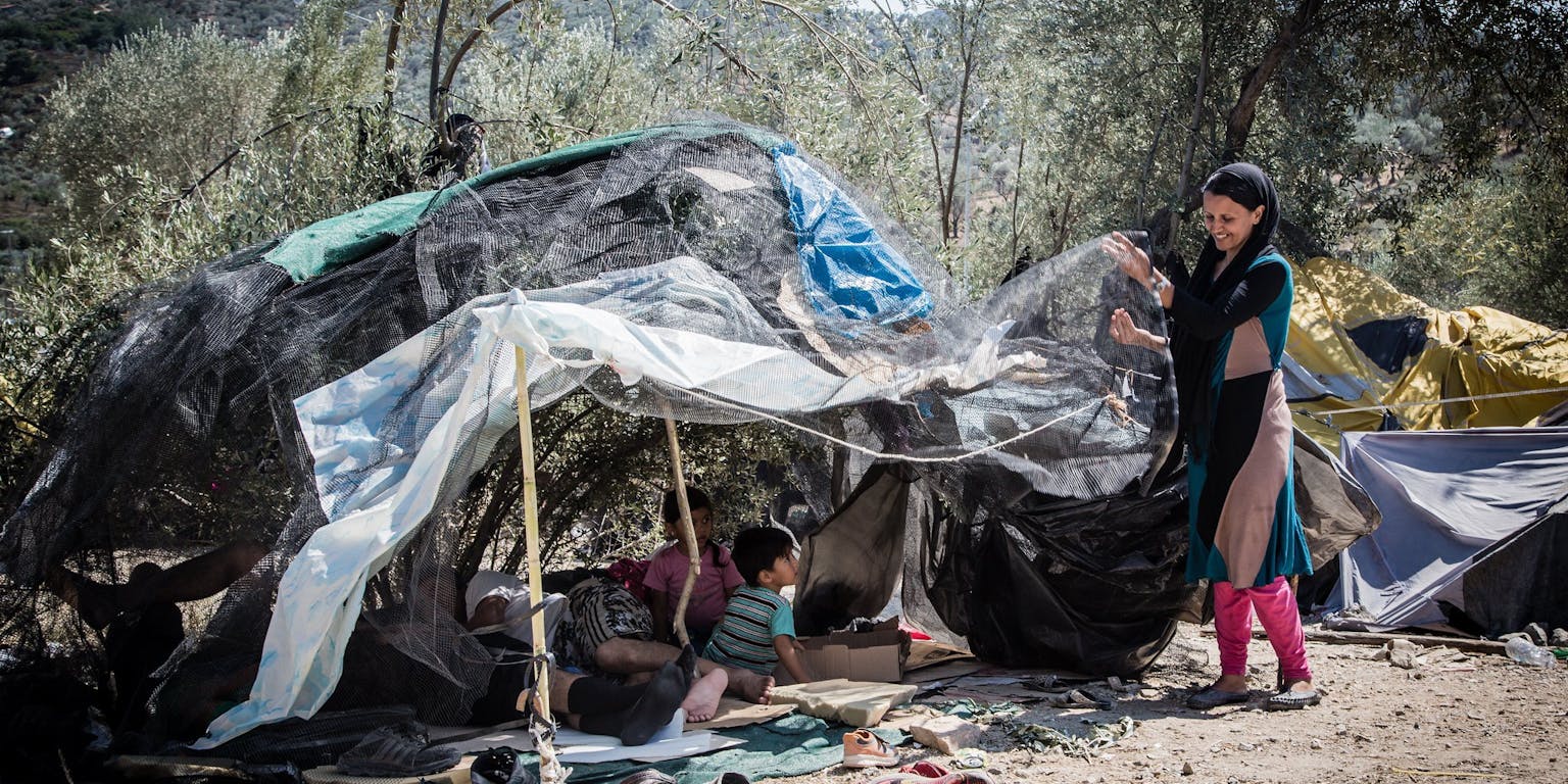 Een groep mensen staat naast een tent in het bos.