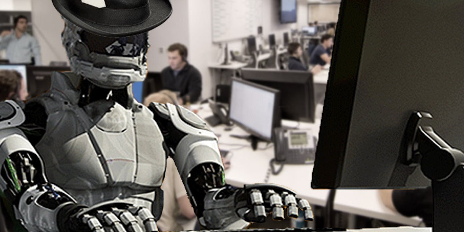Aan een bureau zit een robot met een hoed op.