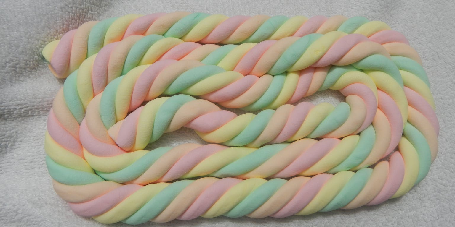 Een kronkel van pastelkleurig spek ligt op een witte deken.