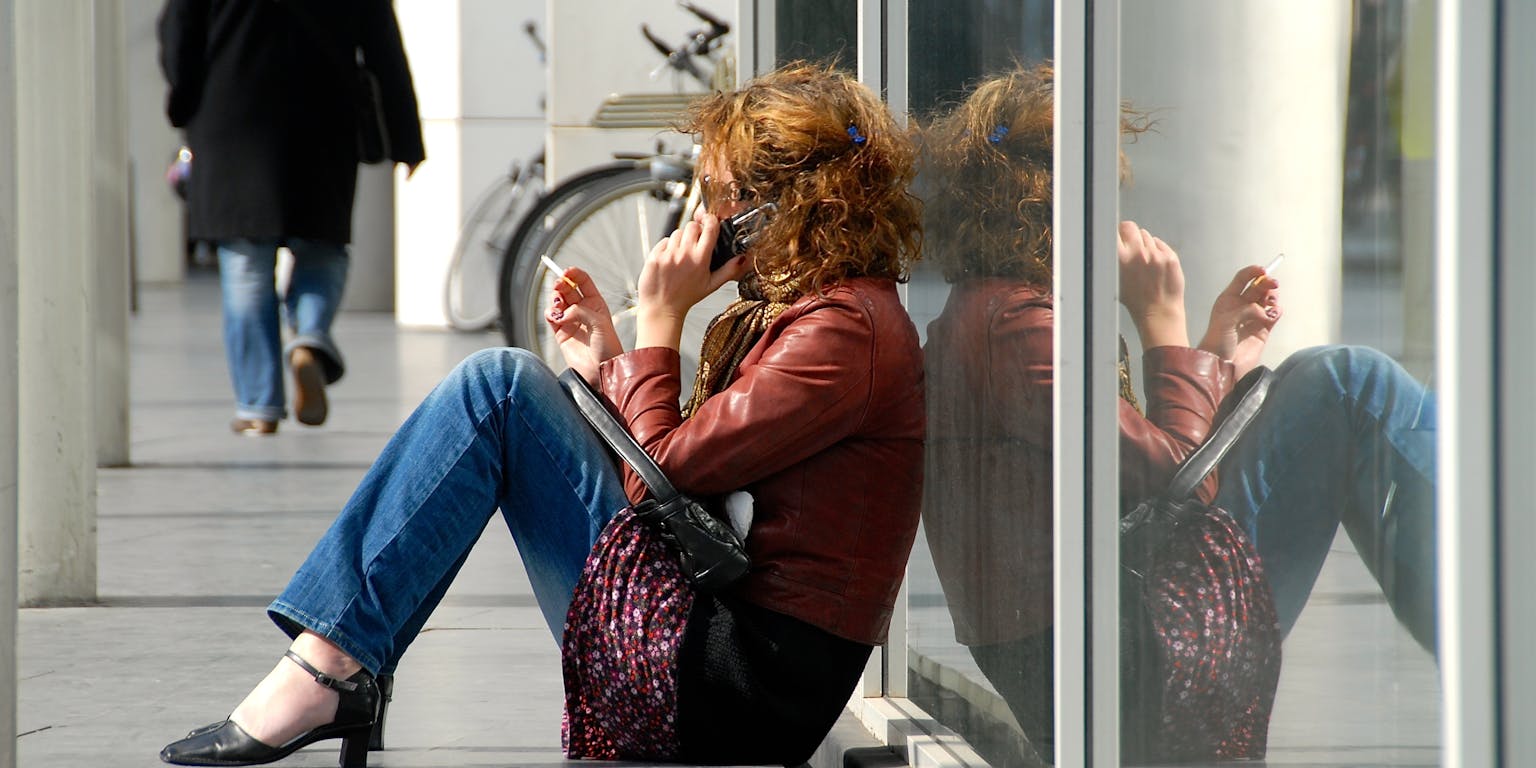 Een vrouw zit op de grond en belt.