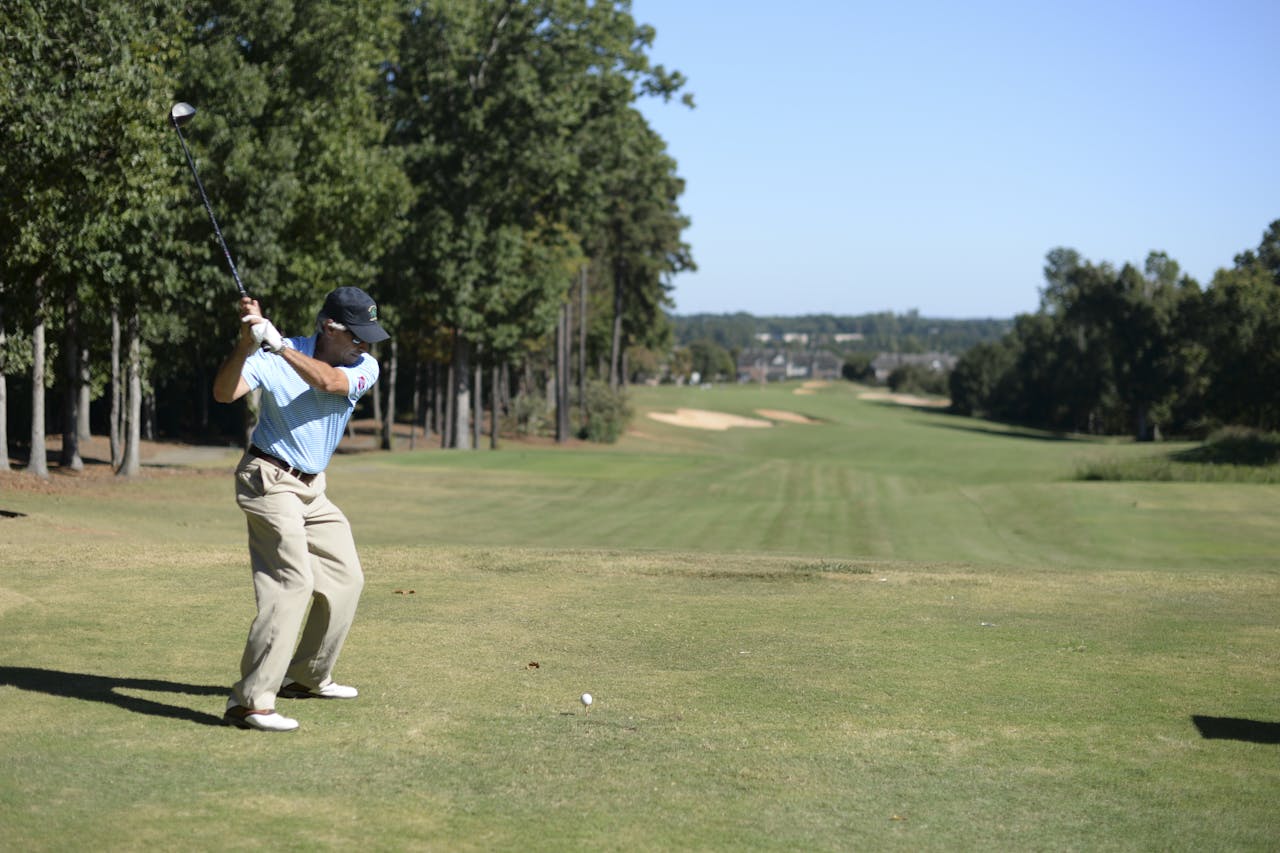 Een man zwaait met een golfclub op een golfbaan.