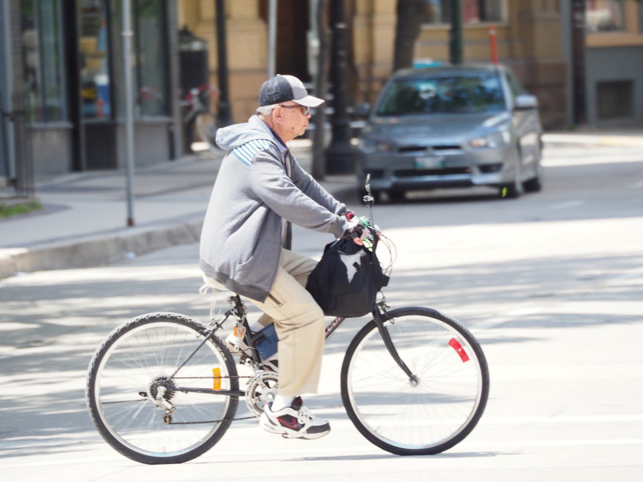 Een oudere man fietst door de straat.