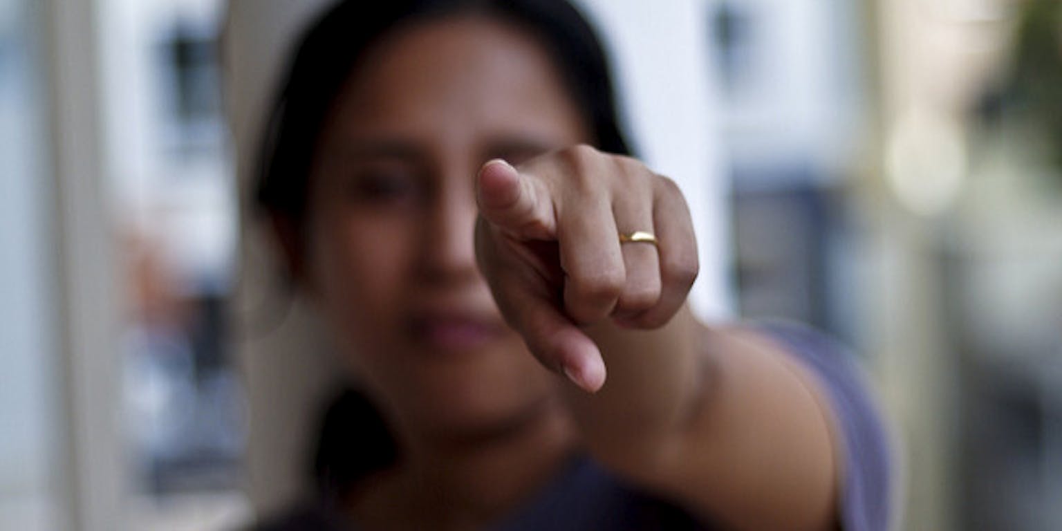 Een vrouw die met haar vinger naar de camera wijst.