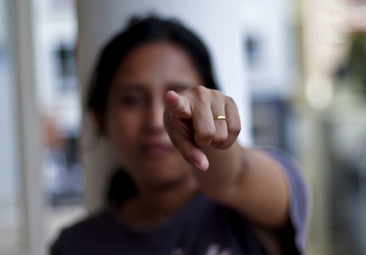 Een vrouw die met haar vinger naar de camera wijst.