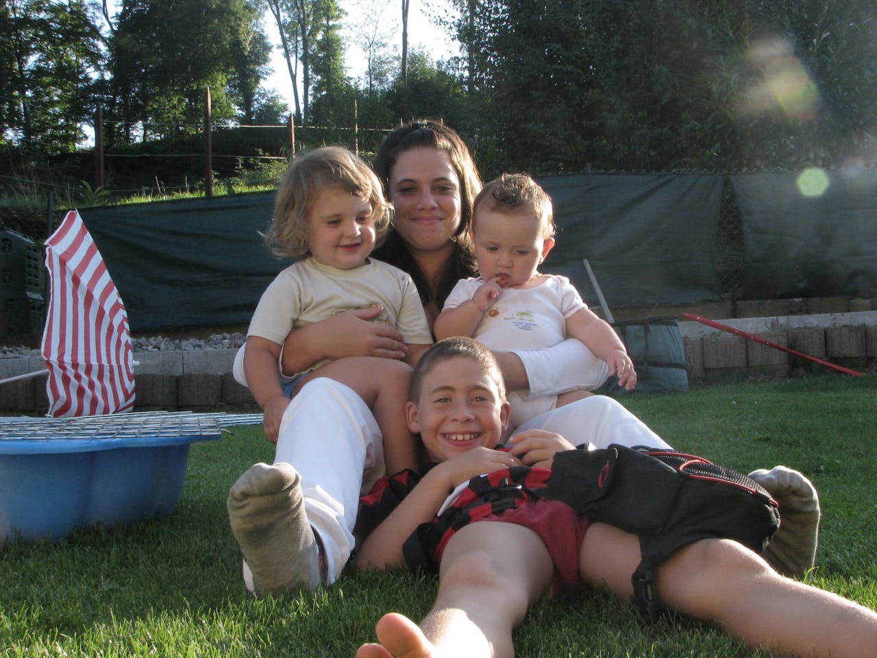 Een vrouw en drie kinderen zitten in het gras.