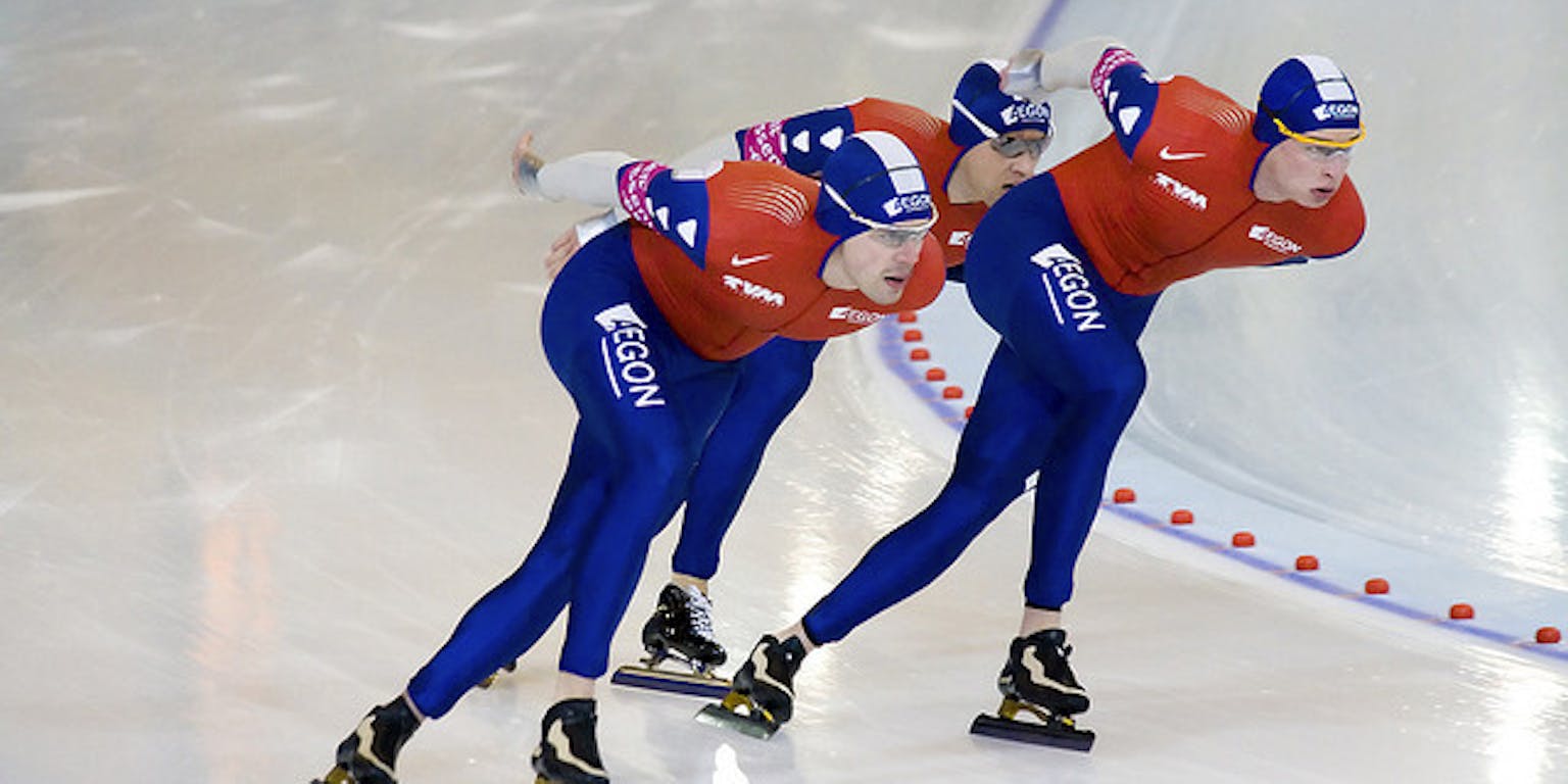 Drie schaatsers op een baan.