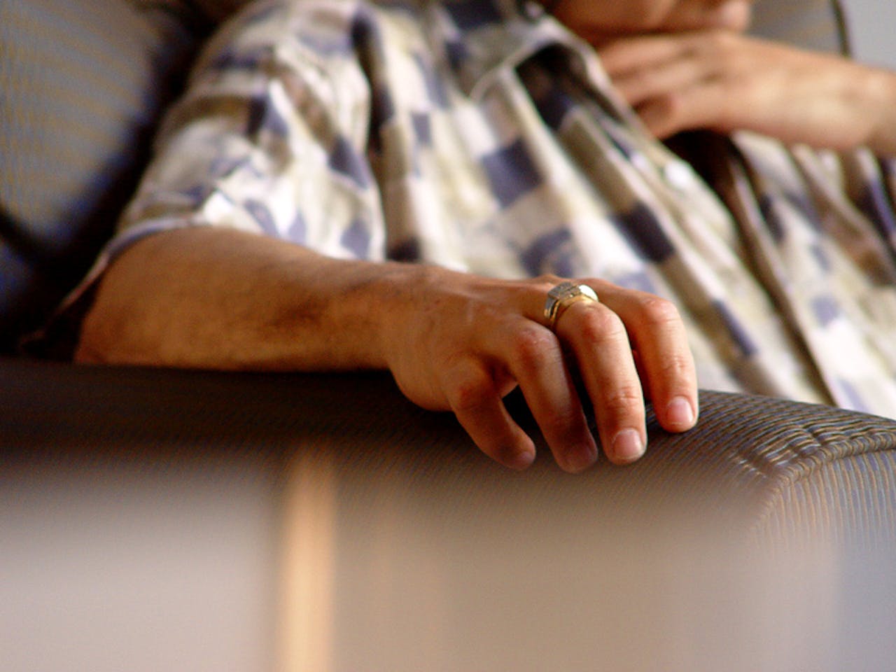 Een close up van een arm van een persoon die op de leuning van een bank rust.