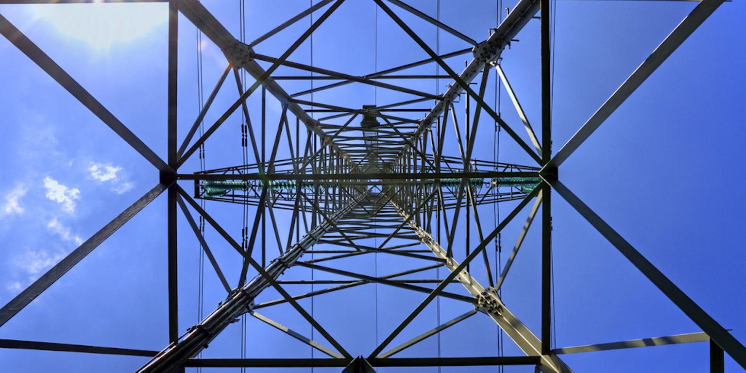 Een foto vanaf onderen van een hoogspanningsmast.