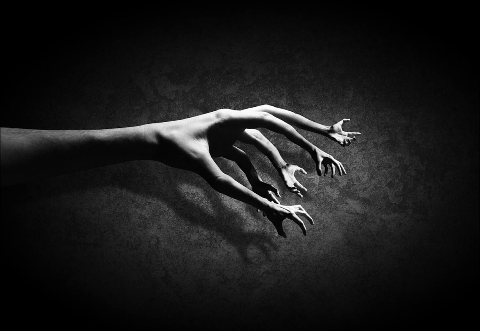 Een artistieke zwart-witfoto van een hand waarvan de vingertoppen handen zijn.