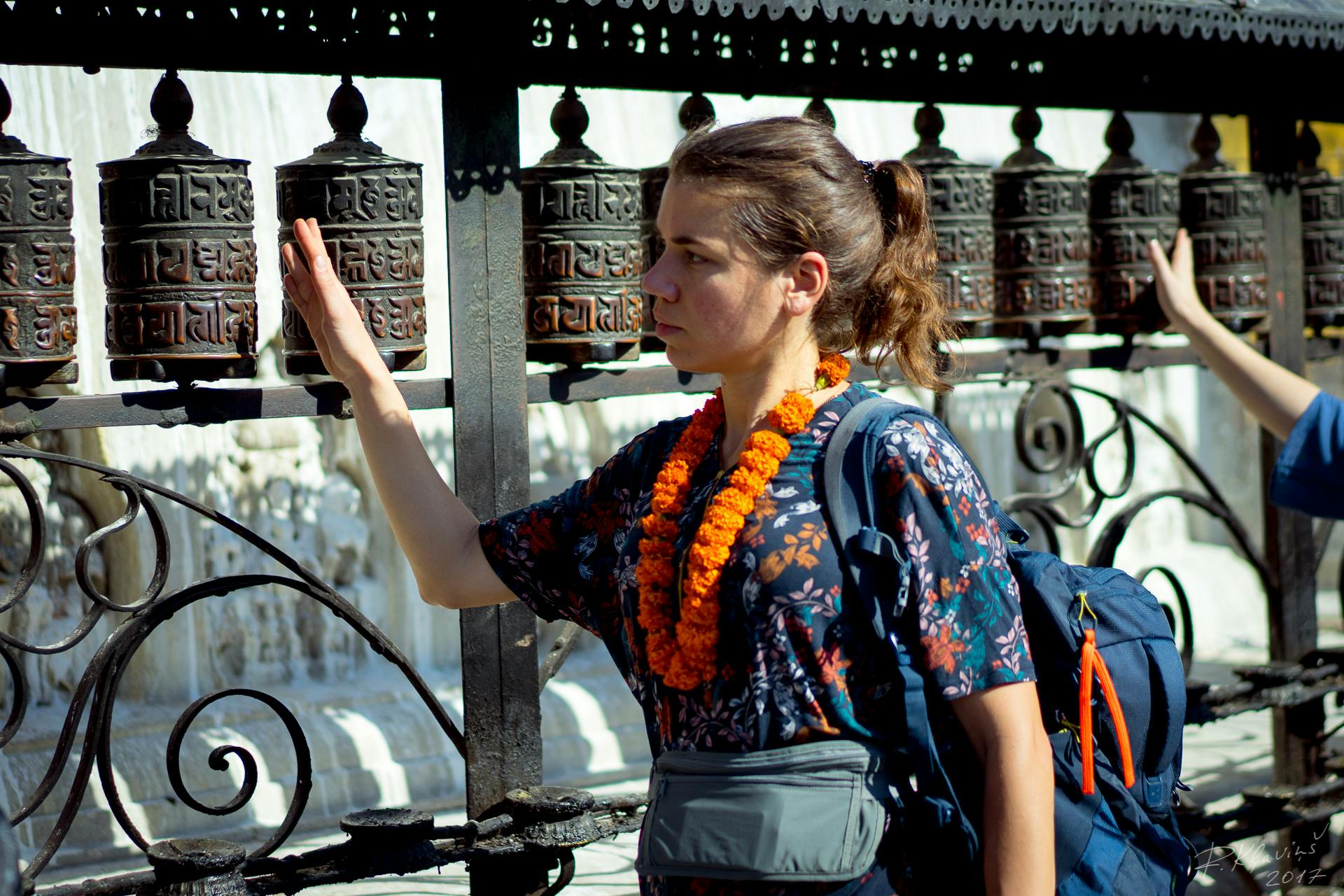 Een vrouw met een rugzak die naar gebedsmolens kijkt.