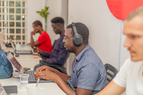 Afrikaanse softwareontwikkelaars zitten naast elkaar te werken op een laptop.