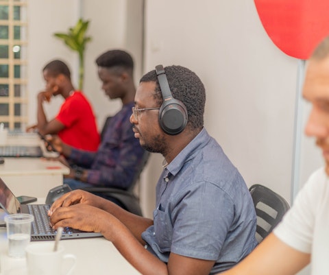 Afrikaanse softwareontwikkelaars zitten naast elkaar te werken op een laptop.
