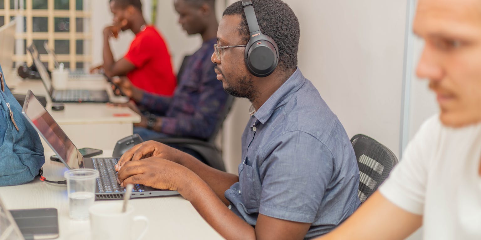 Afrikaanse softwareontwikkelaars zitten naast elkaar te werken op een laptop.