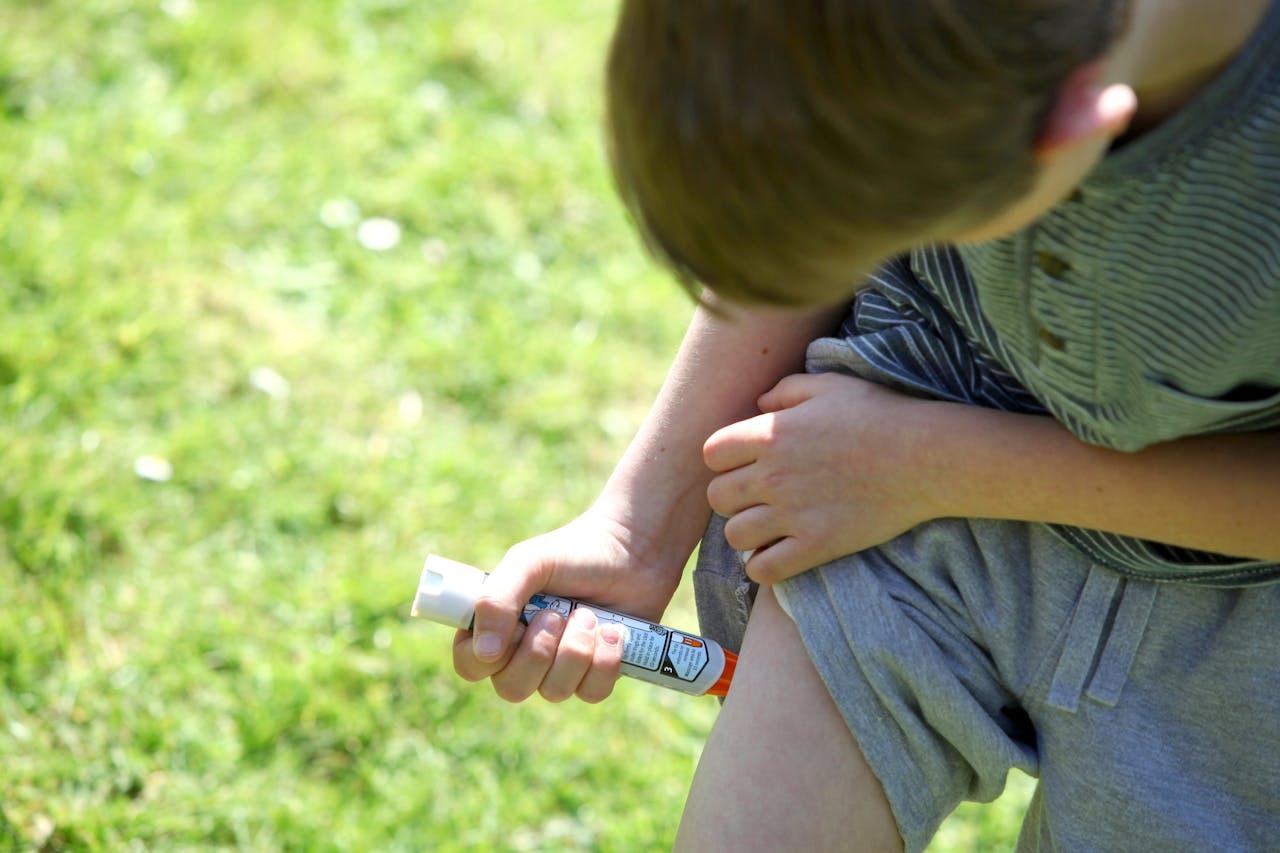 Een jongen die een epipen in zijn been doet, om een ernstige allergische reactie te voorkomen.