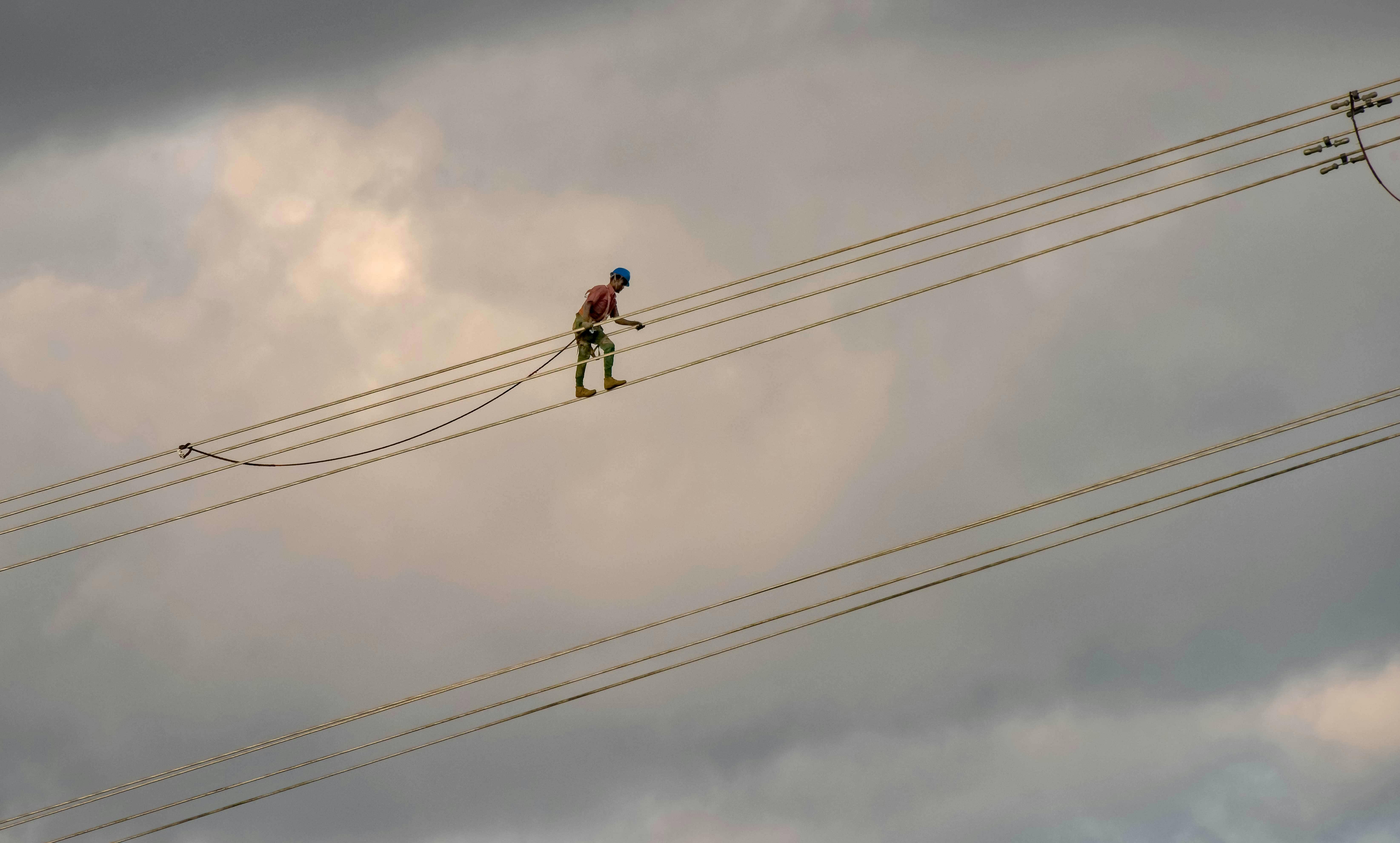 Iemand die op grote hoogte op kabels loopt.