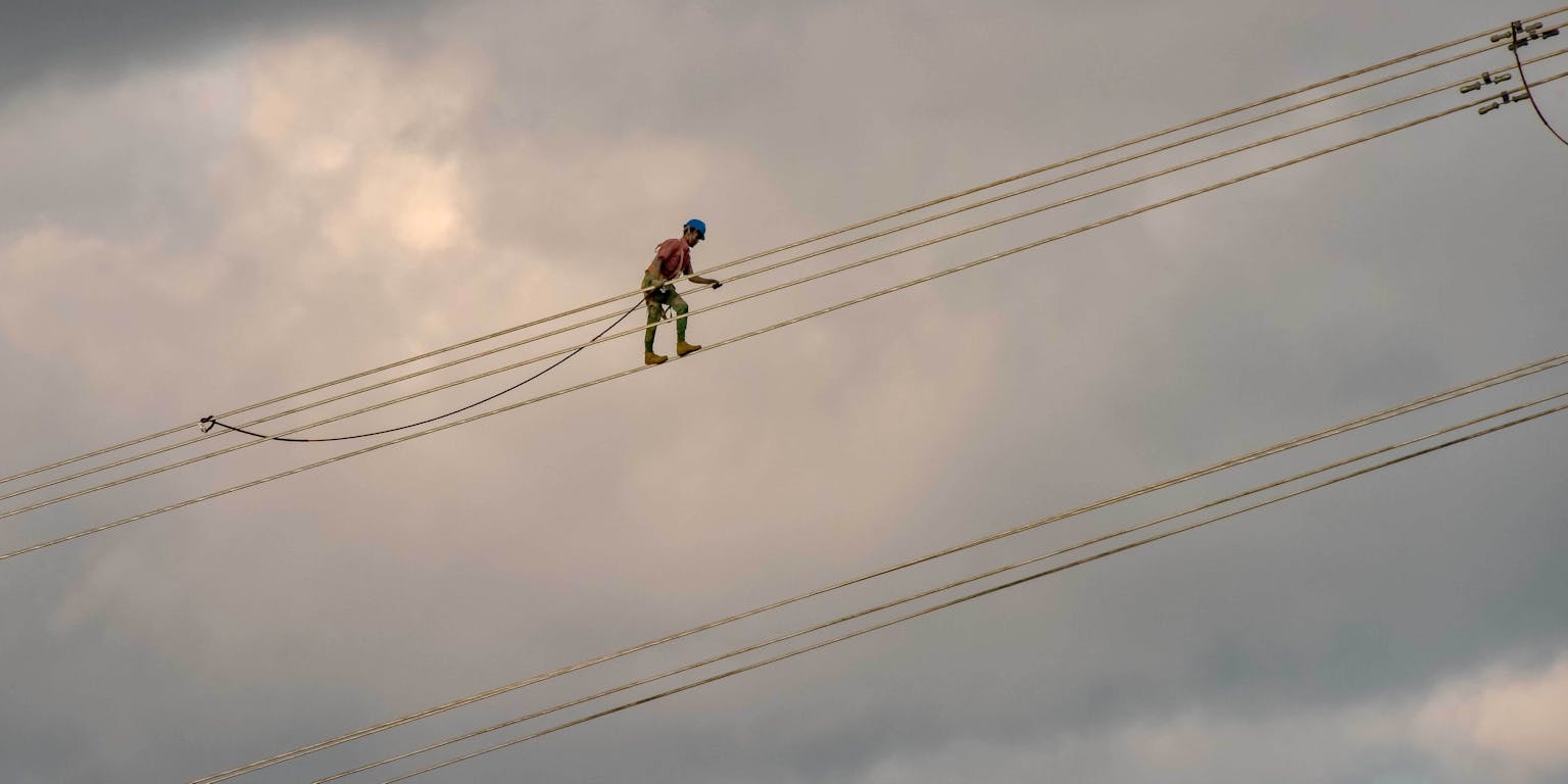 Iemand die op grote hoogte op kabels loopt.