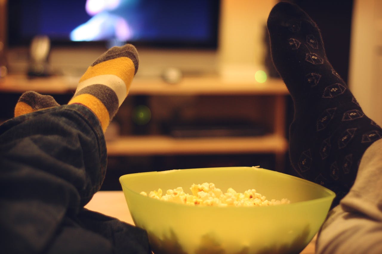 Een close-up van een bak popcorn met een tv op de achtergrond.