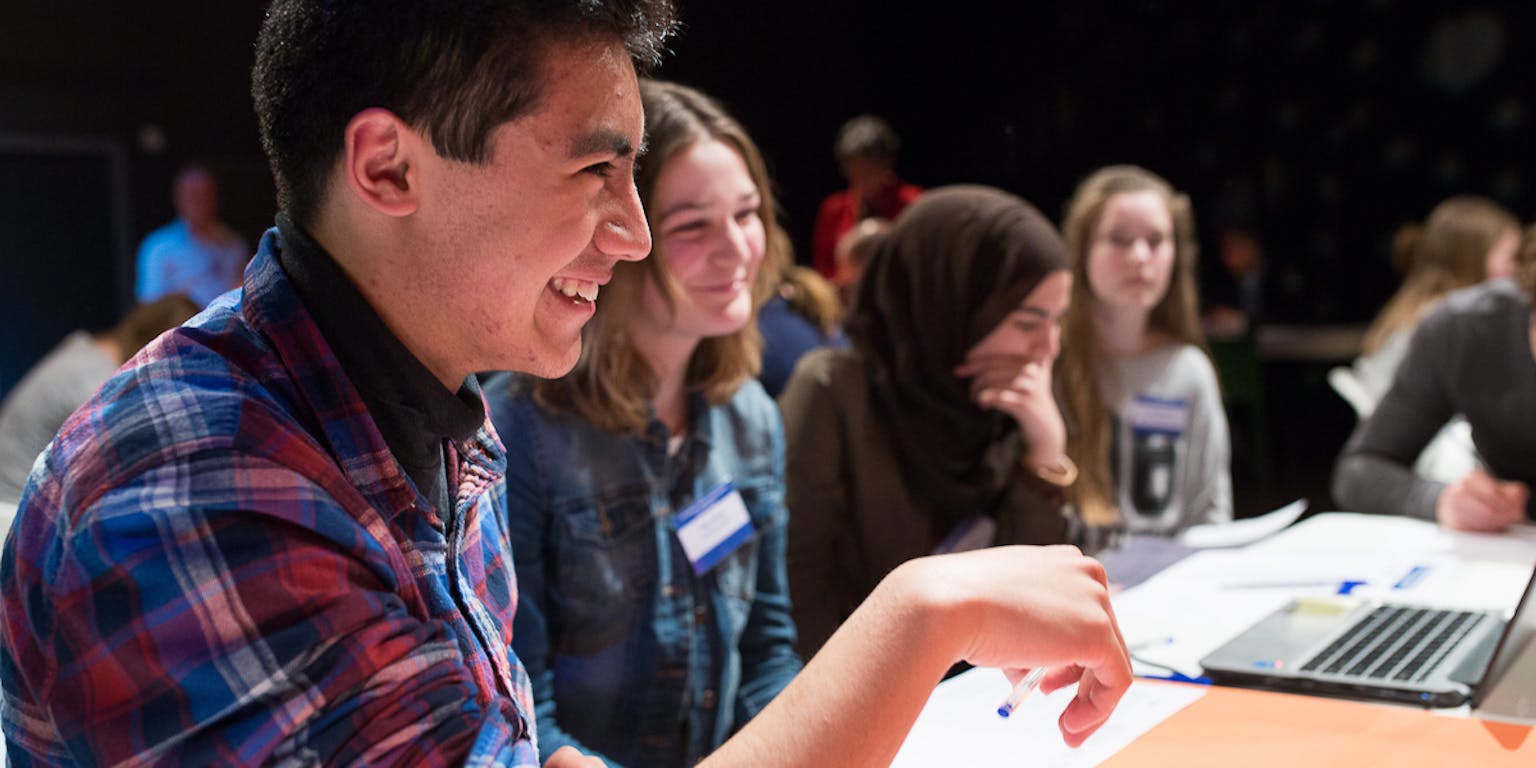 Een groep studenten in beeld. Er liggen markeerstiften en een opengeklapte laptop op tafel.