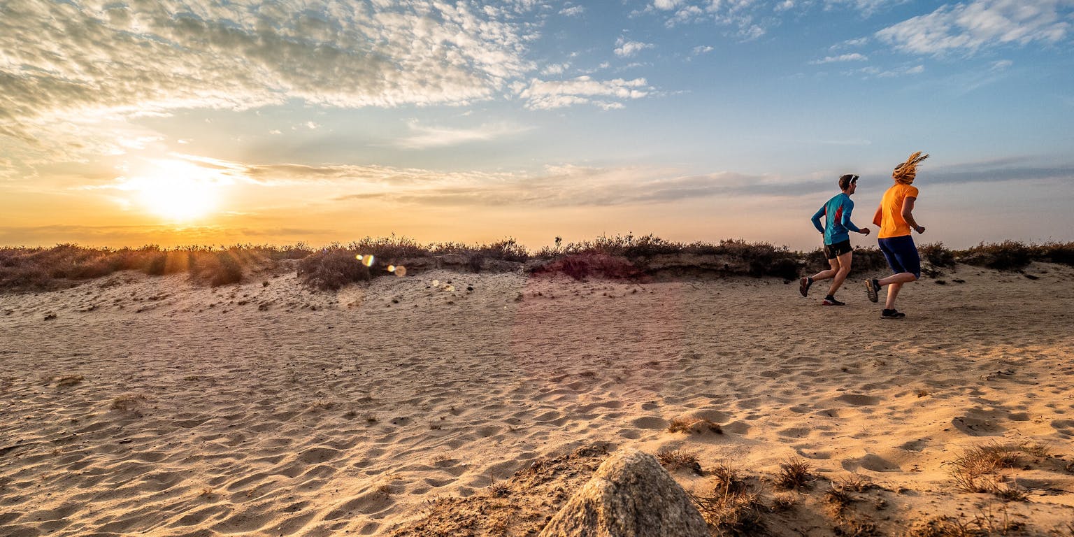 Bij zonsondergang rent een man over het strand.