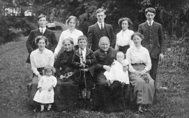 Zwart-wit foto van een familie aan het begin van de 20e eeuw met in totaal 12 mensen.