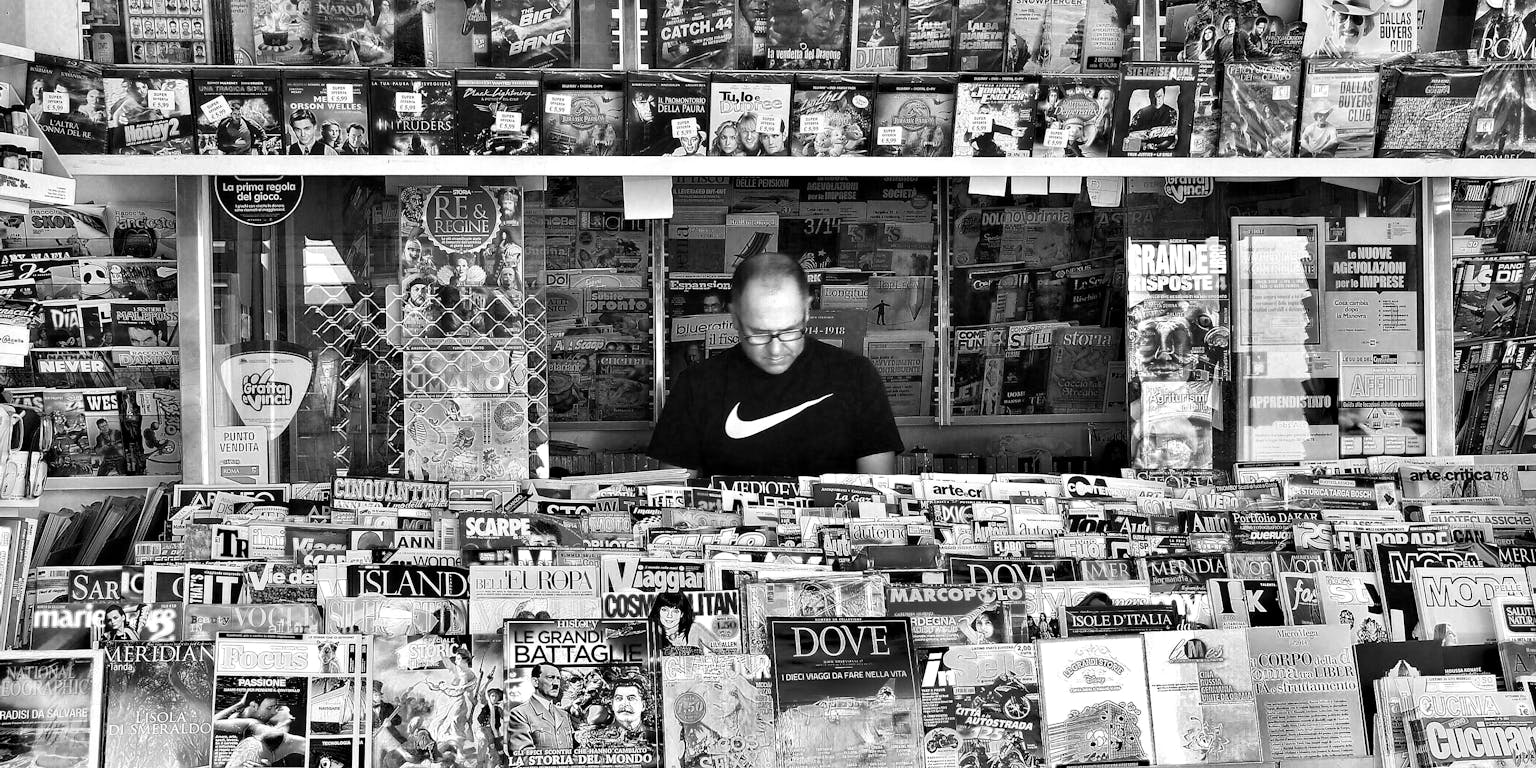Een zwart-witfoto van een man in een krantenkiosk.