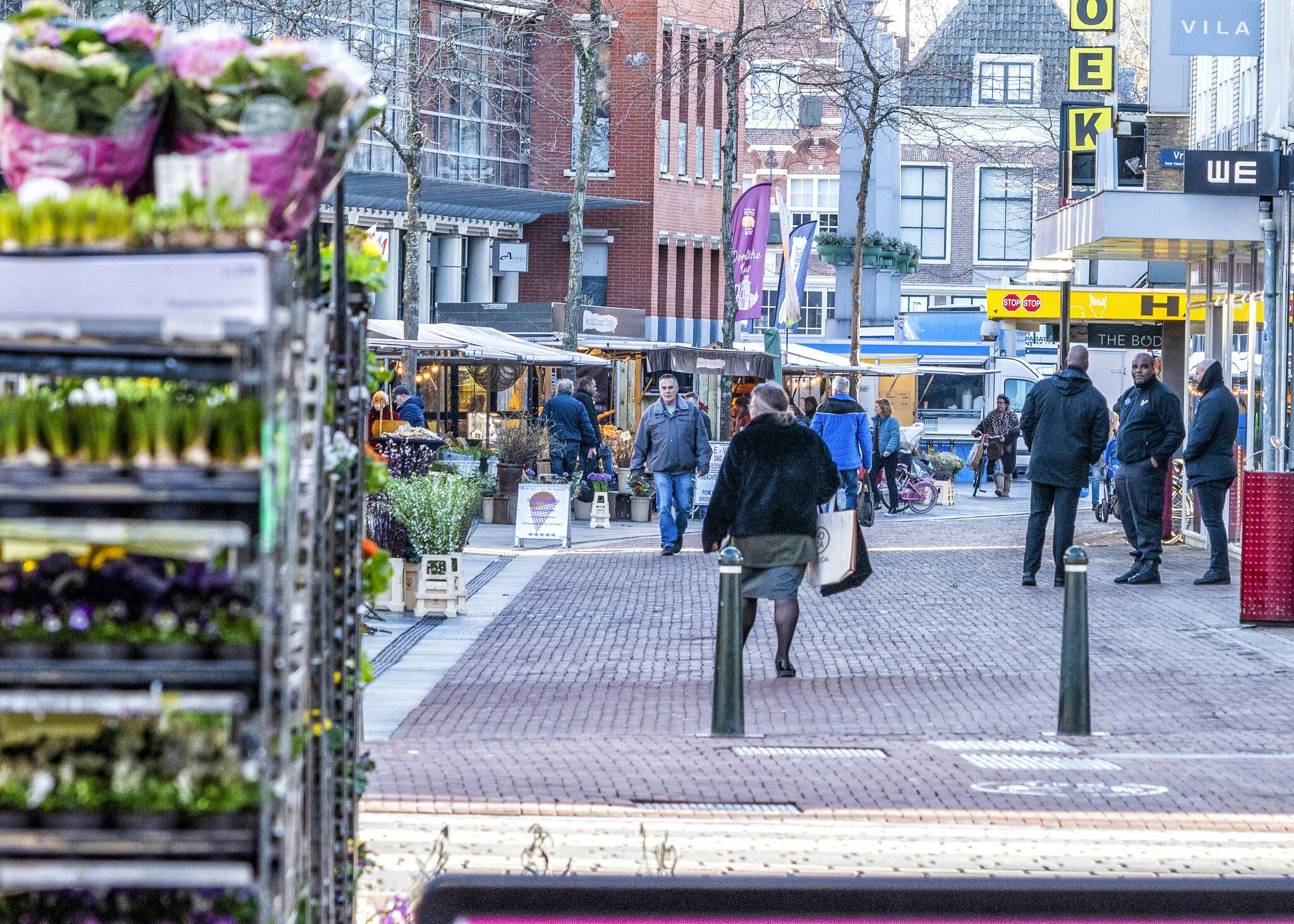 Een straatbeeld met winkels waar veel mensen rondlopen.