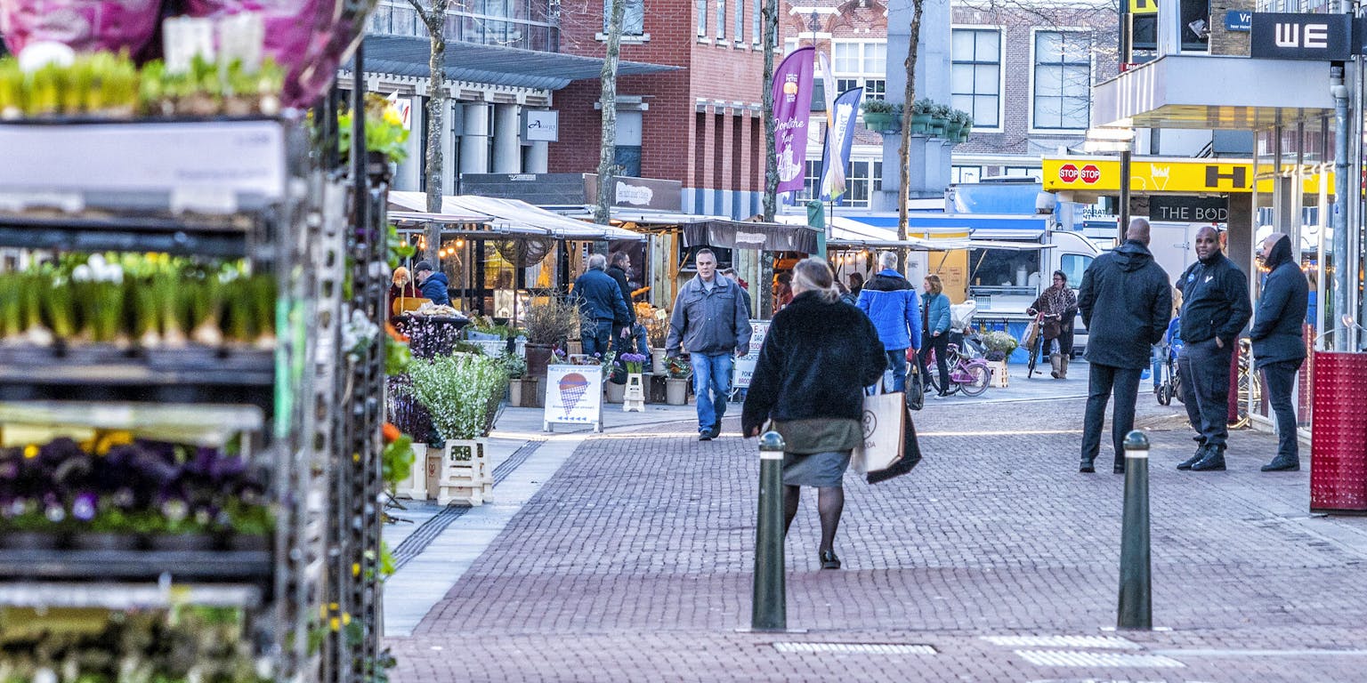 Een straatbeeld met winkels waar veel mensen rondlopen.