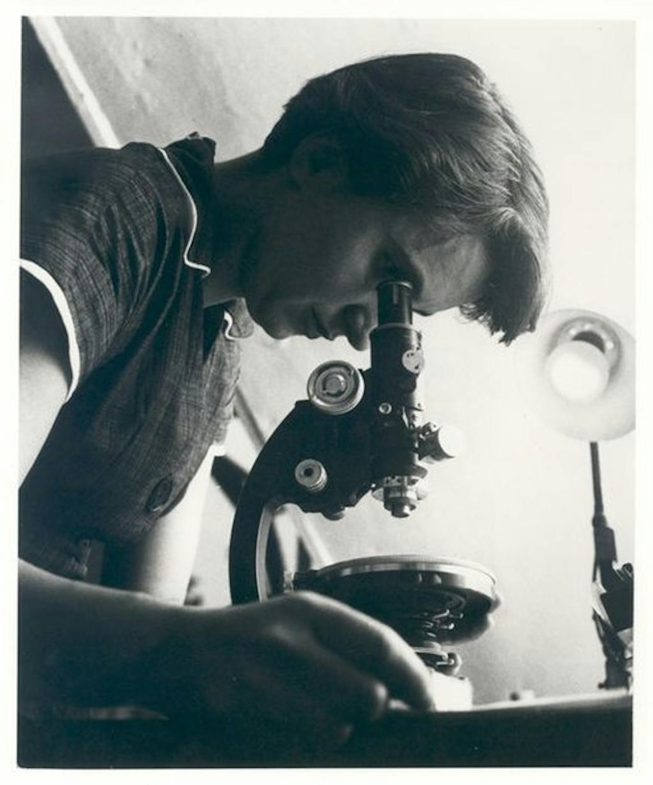 Rosalind Franklin kijkt door een microscoop