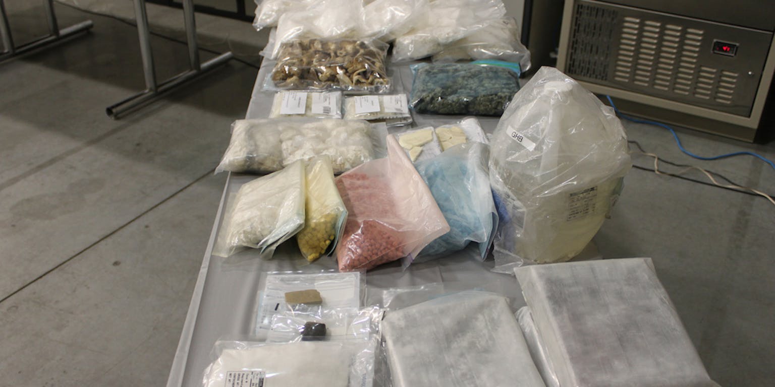 Een tafel met veel verschillende zakken met drugs erop.