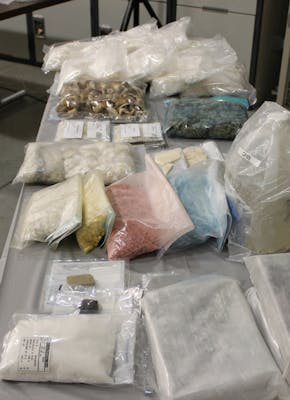 Een tafel met veel verschillende zakken met drugs erop.
